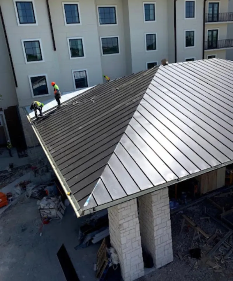 Crew installing standing seam metal roof panels on a commercial project in Cameron Park